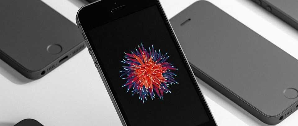 A black phone surrounded by others on a white surface.